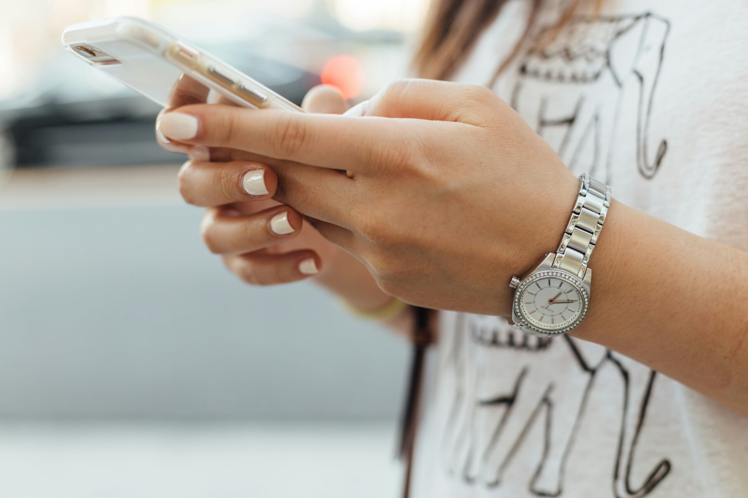屋外でスマートフォンを操作する女性の手元