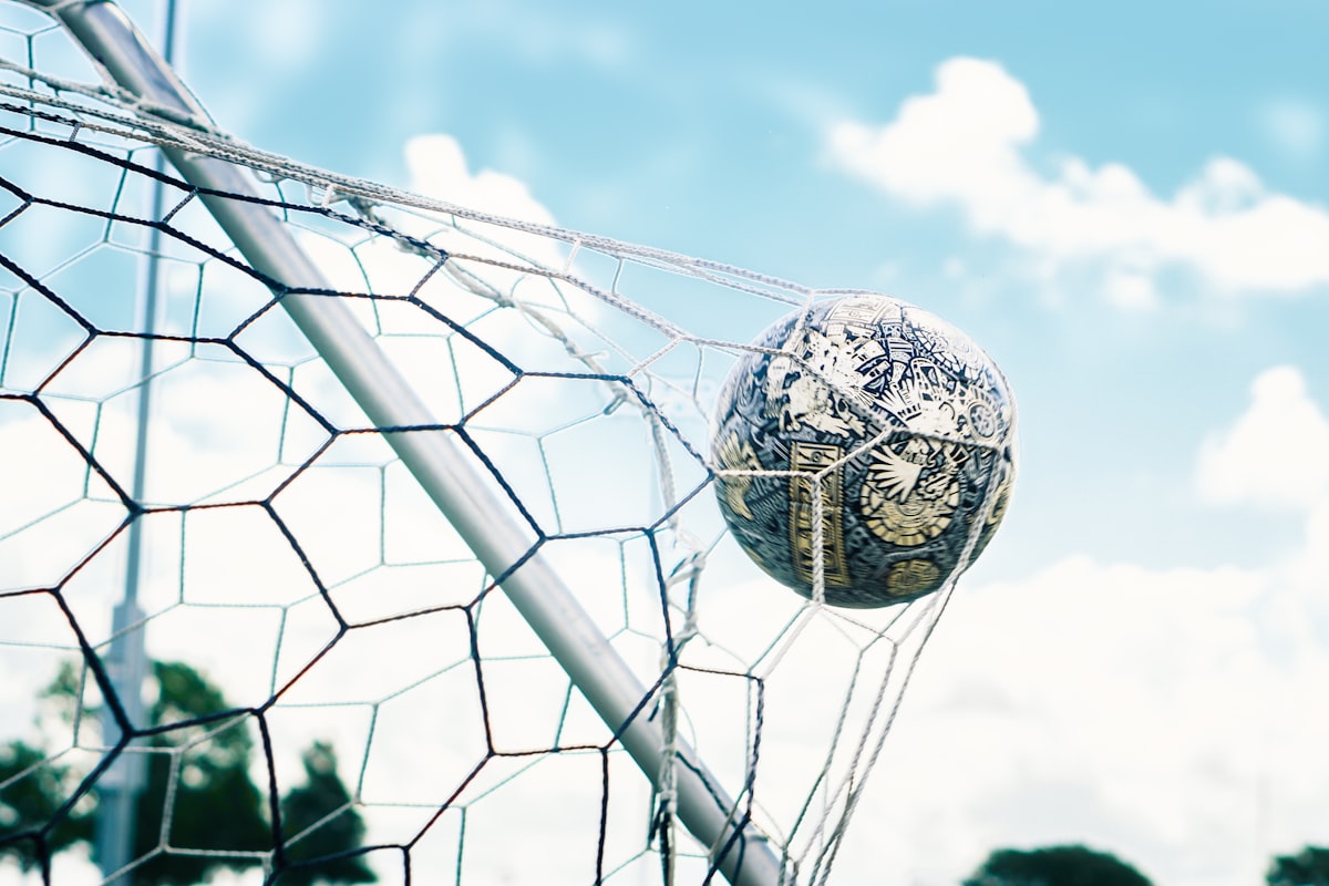 ゴールネットに入るサッカーボール(青空背景・ゴールシーン)