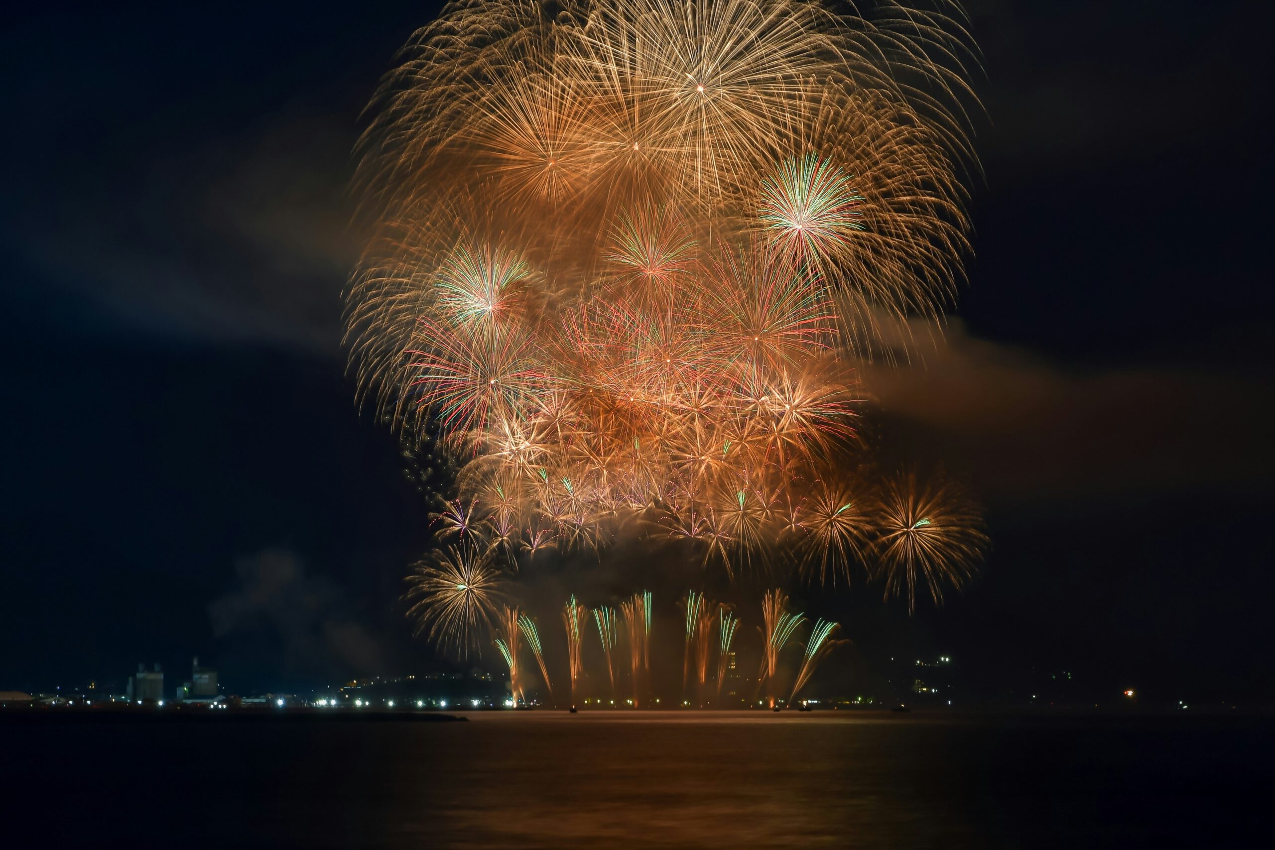 夜の水辺に打ち上がる花火のイメージ