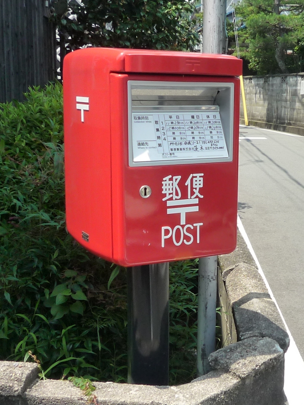 日本の街角に設置された赤い丸型の郵便ポスト