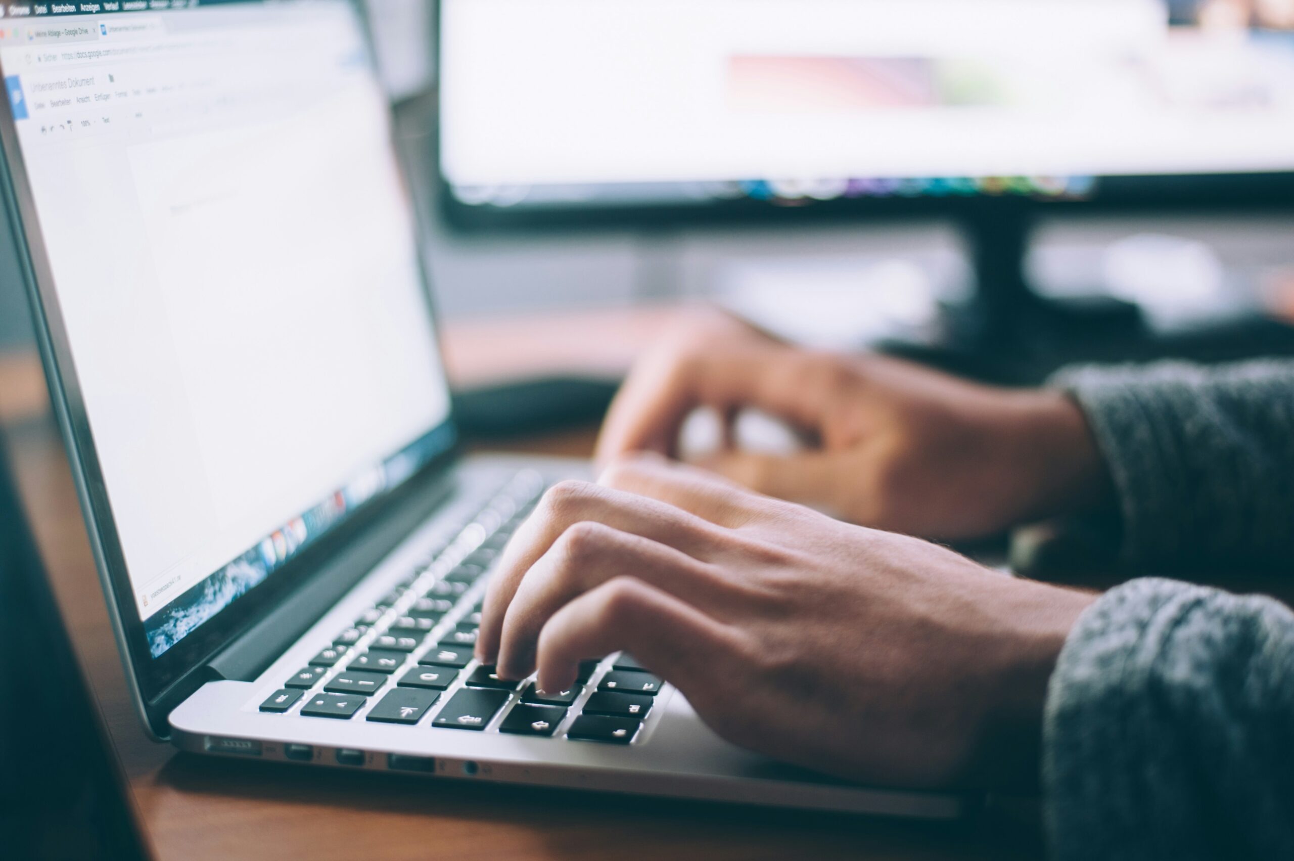 MacBookを操作してオフィスでメール対応をしている人物