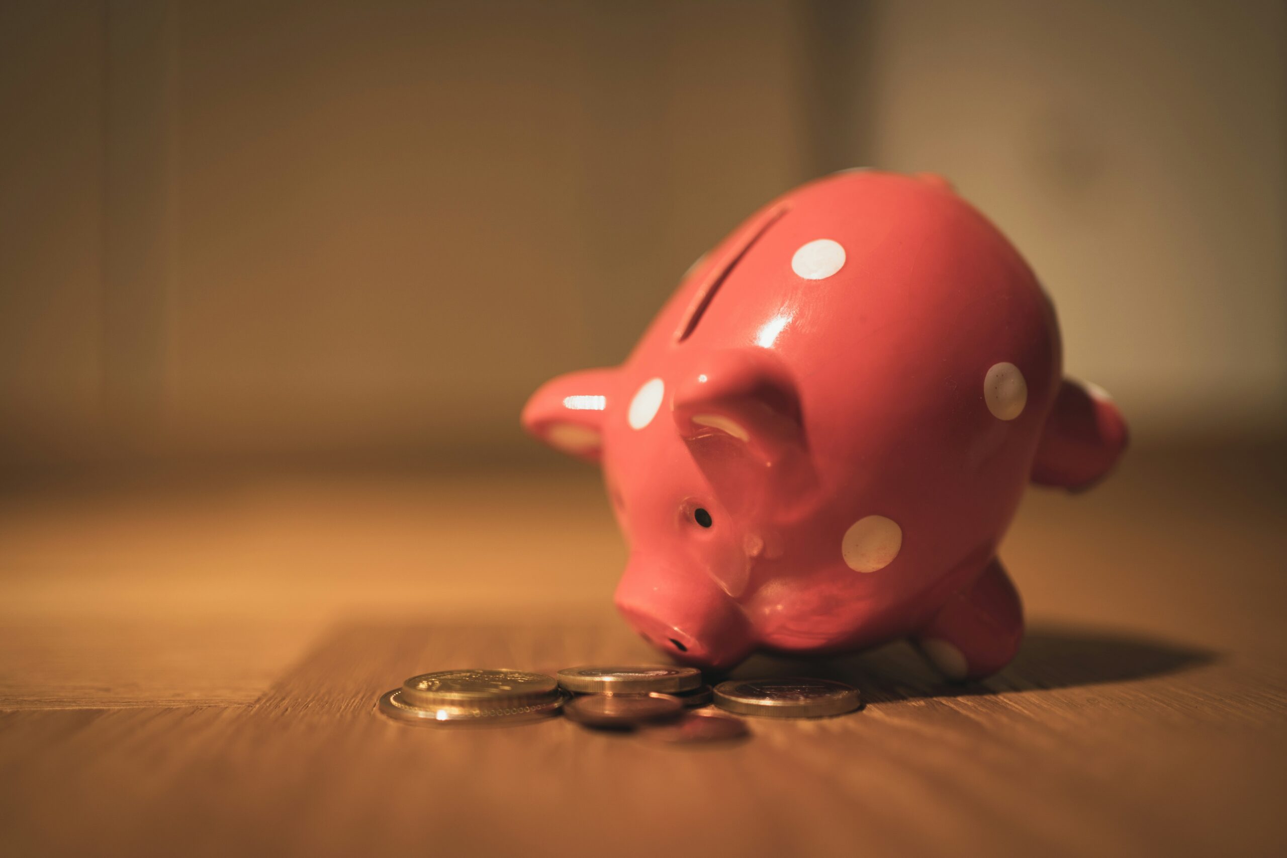 老後資産の積み立てをイメージした、木製テーブルの上のピンクの豚の貯金箱