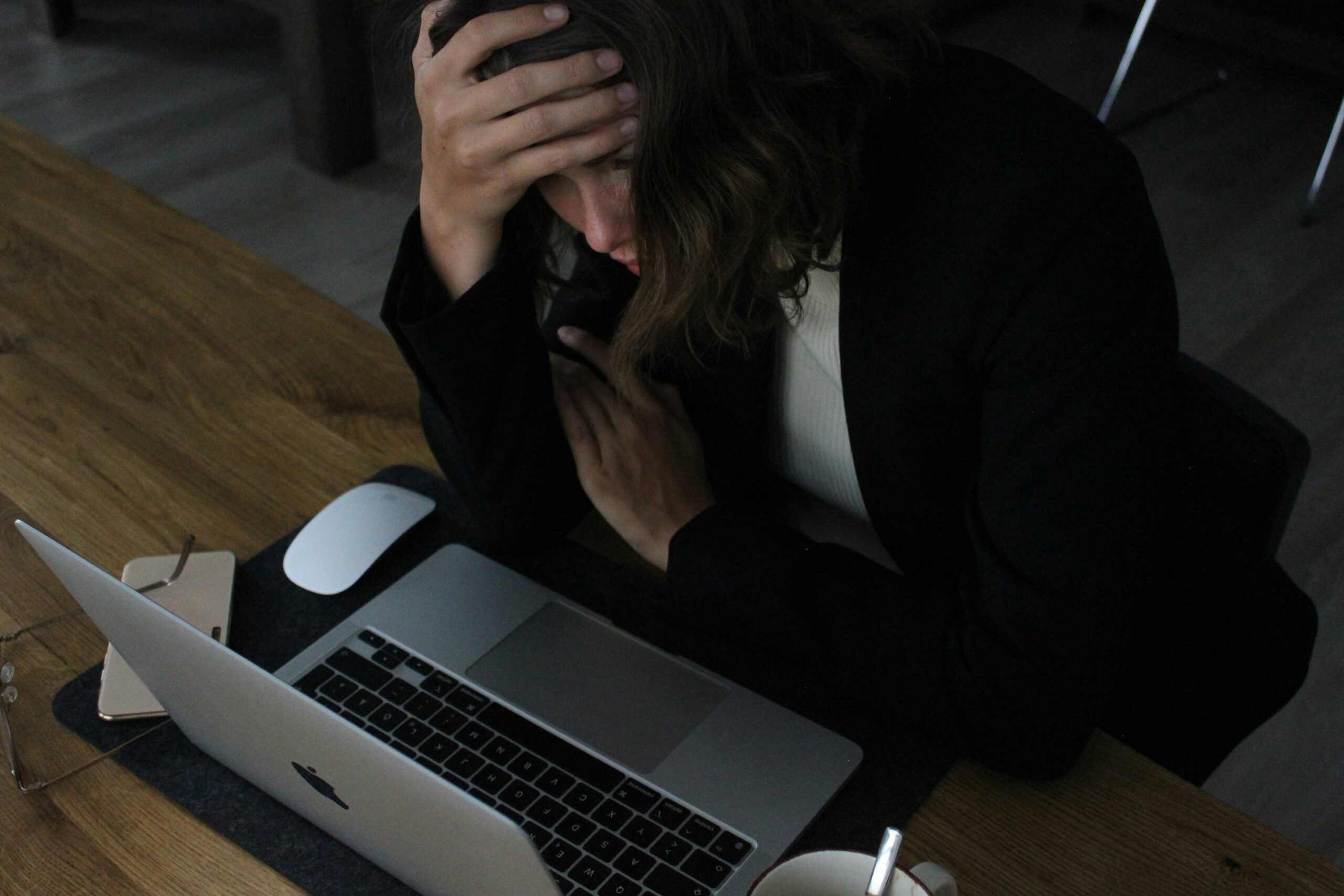 ノートPCの前で送受信エラーに困っている女性